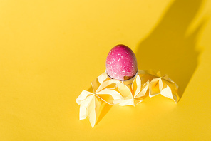origami flowers near painted easter egg on yellow