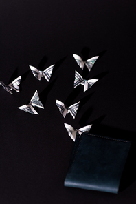 decorative money origami butterflies near wallet isolated on black