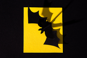 top view of origami bat on yellow paper isolated on black