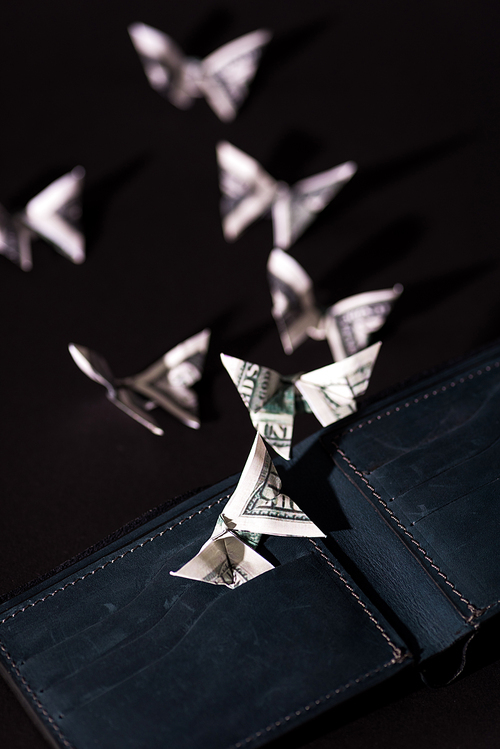selective focus of money origami butterflies near wallet isolated on black