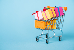 small gift boxes in toy shopping cart on blue