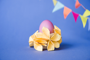selective focus of origami flowers near easter egg on blue
