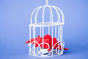origami birds in metallic cage on blue