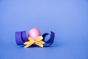 origami flower near painted easter egg on blue