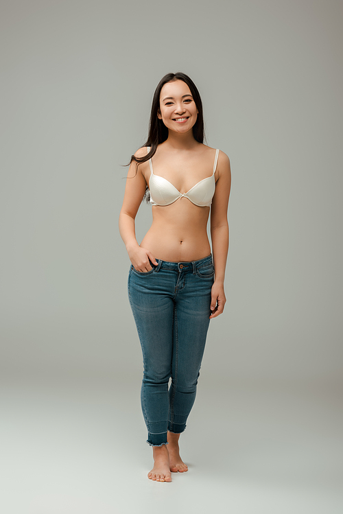 happy overweight asian woman standing with hand in pocket on grey