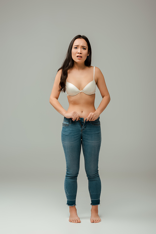 shocked and overweight asian girl wearing jeans on grey