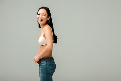 happy and overweight asian girl wearing jeans isolated on grey