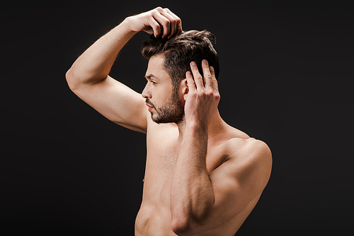 bearded handsome nude man combing hair isolated on black