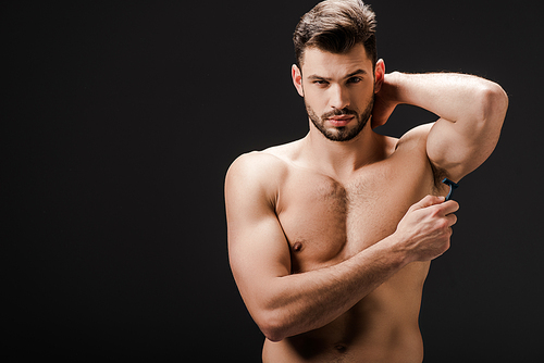handsome naked man shaving armpits with razor isolated on black