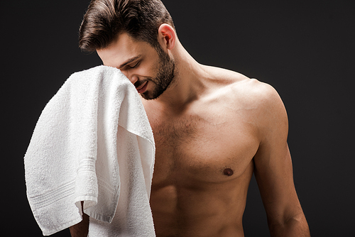 happy handsome naked man with towel isolated on black