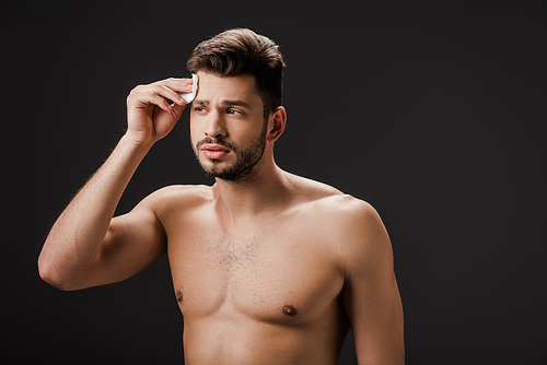 handsome sexy naked man using cosmetic cotton pad isolated on black