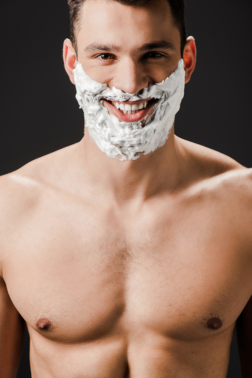 cheerful naked man with shaving foam on face isolated on black