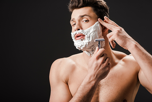 sexy naked man shaving face with razor isolated on black