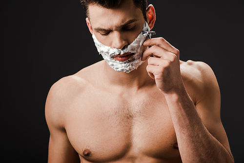 sexy nude man shaving face with razor isolated on black