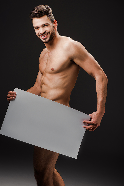 smiling sexy naked man holding blank placard isolated on black