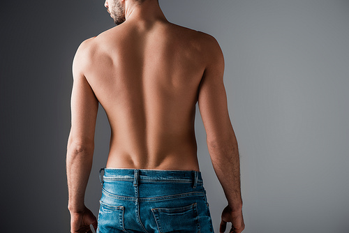 Back view of sexy shirtless man in jeans on grey
