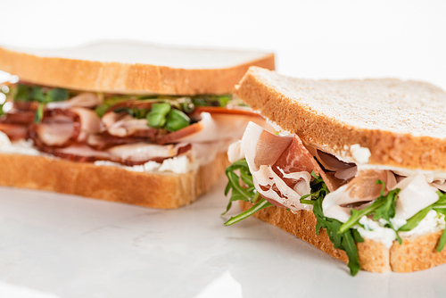 selective focus of fresh sandwich with arugula and prosciutto on white surface