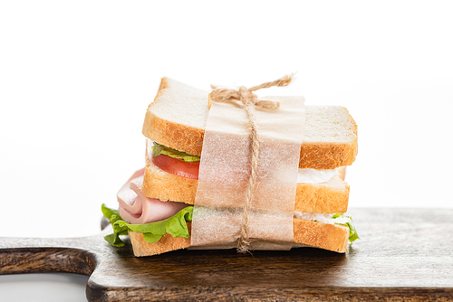 fresh delicious sandwich with sliced sausage and lettuce on wooden cutting board on white surface