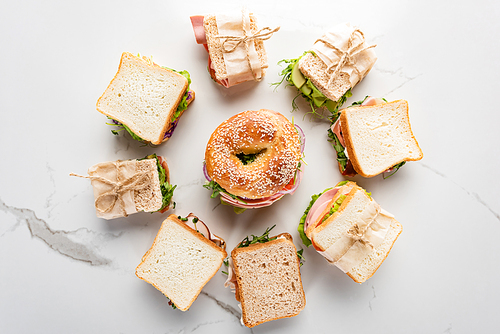 top view of fresh sandwiches around bagel on marble white surface