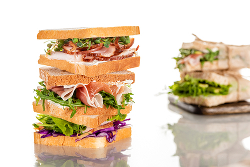 selective focus of fresh sandwiches with arugula and meat on white surface