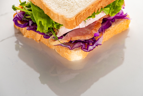 close up view of fresh green sandwich with meat on marble white surface