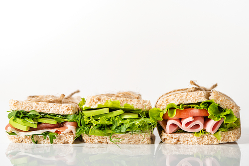 fresh green sandwiches with avocado and meat on white surface