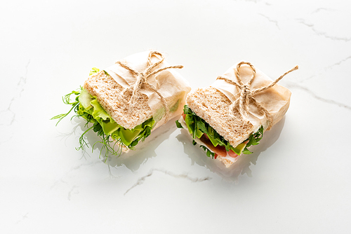 fresh green sandwiches with avocado and jamon on marble white surface