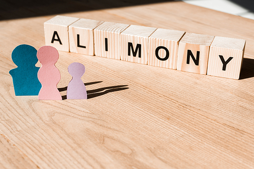 wooden blocks with alimony lettering near family paper people on textured surface