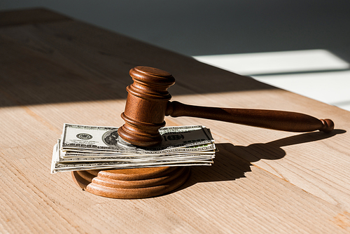 wooden table with gavel on dollar banknotes