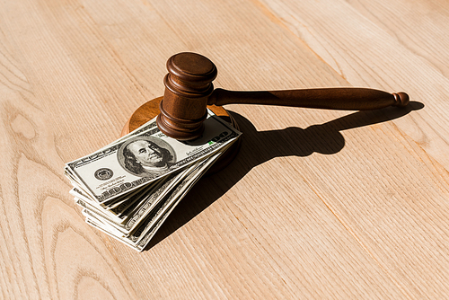 wooden gavel on dollar banknotes and textured table