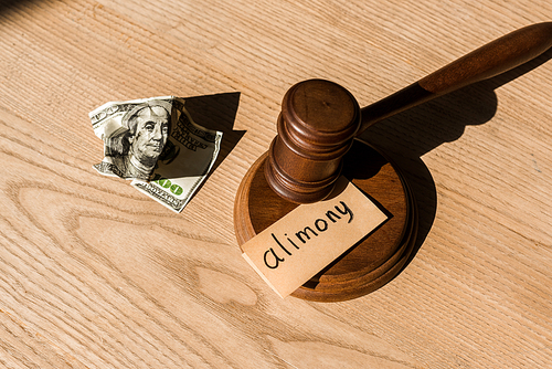 top view of wooden gavel near dollar banknote and paper with alimony lettering on desk