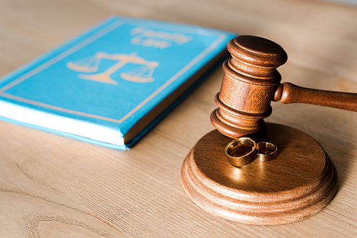 selective focus of gavel near engagement rings and book on desk