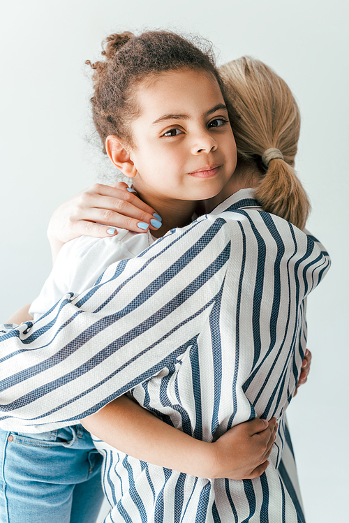 back view of foster mother hugging cute african american kid isolated on white