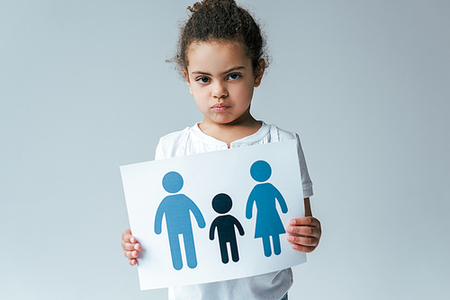 serious african american kid holding paper with drawn family isolated on grey, adoption concept