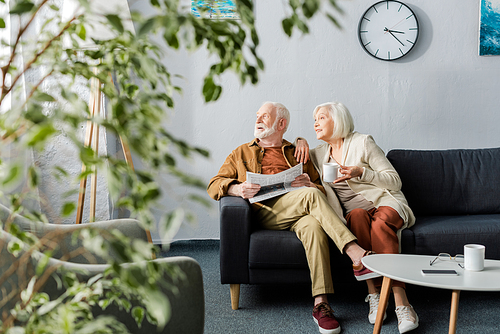 selective focus of senior couple looking away while sitting on sofa