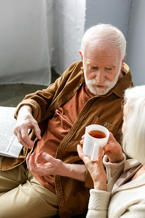 high angle view of senior man talking to wife holding cup of tea