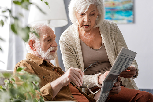 selective focus of attentive senior couple reading newspaper together