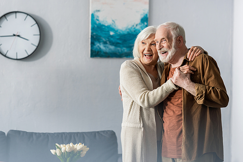 happy senior couple dancing at home and looking away