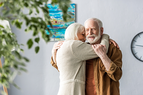 selective focus of happy senior man hugging smiling wife