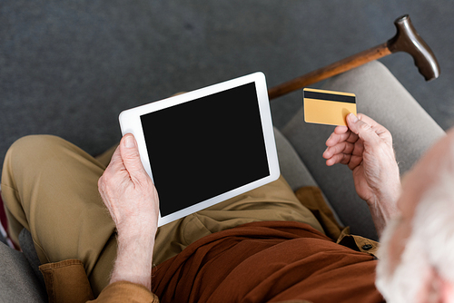 cropped view of senior man holding digital tablet with blank screen and credit card, overhead view