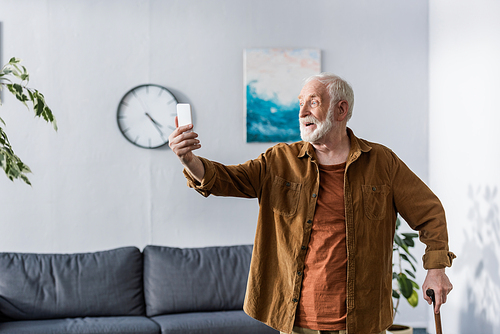 excited senior man smiling while taking selfie on smartphone