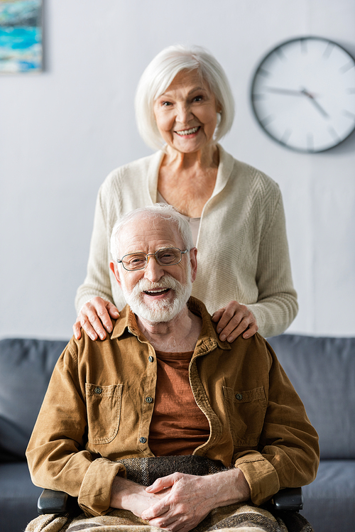 happy senior woman touching shoulders of smiling husband sitting in .