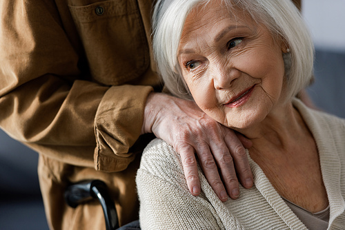 cropped view of senior man touching shoulder of disabled wife