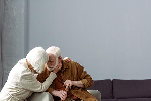 senior woman touching face and hugging husband sick on dementia