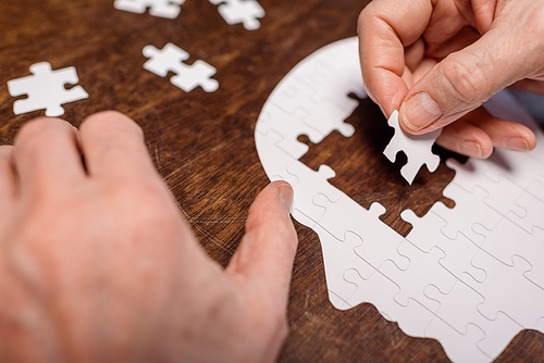 cropped view of sick senior man combining jigsaw puzzle for dementia therapy