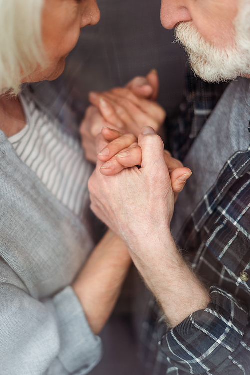 cropped view of senior woman and her husband, sick on dementia, holding hands