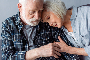 senior woman hugging and leaning on old man with dementia disease