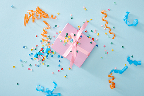 top view of colorful confetti near pink gift box on blue background