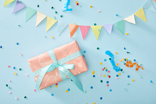 top view of colorful confetti near gift box on blue background