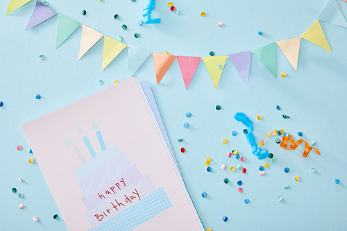 top view of colorful confetti near birthday greeting card on blue background